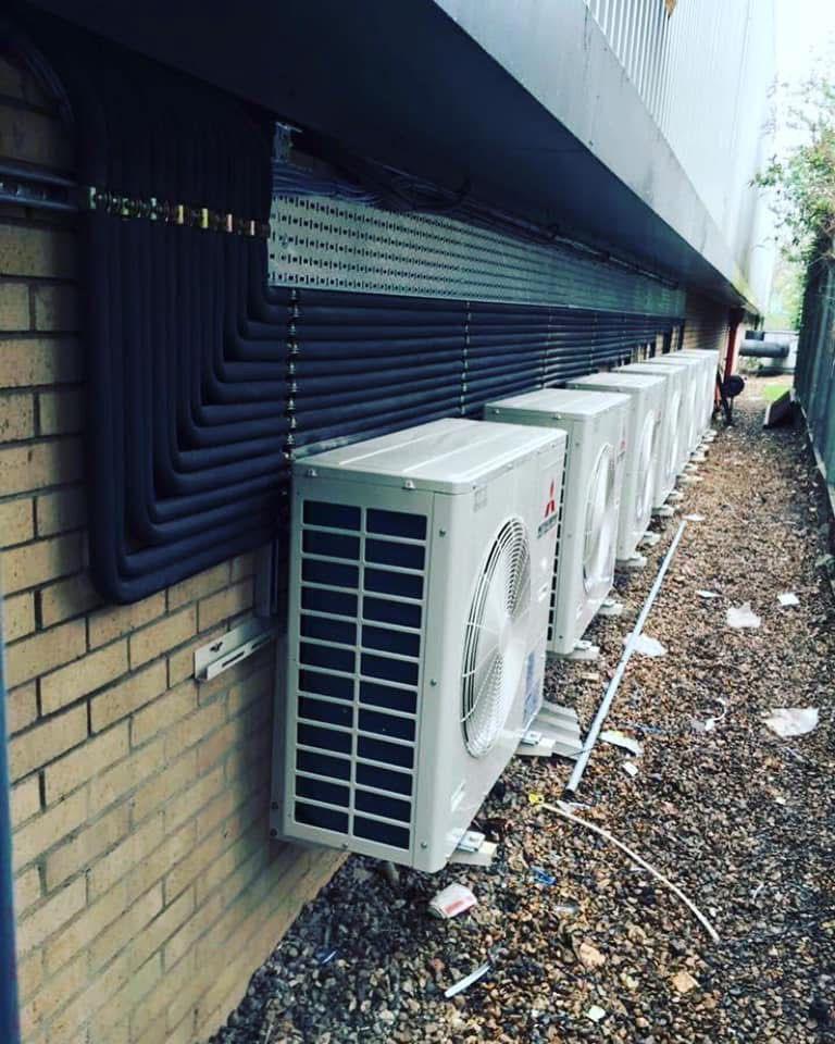 Row of commercial air conditioning condensers maintained by Air Logic Climate Solutions