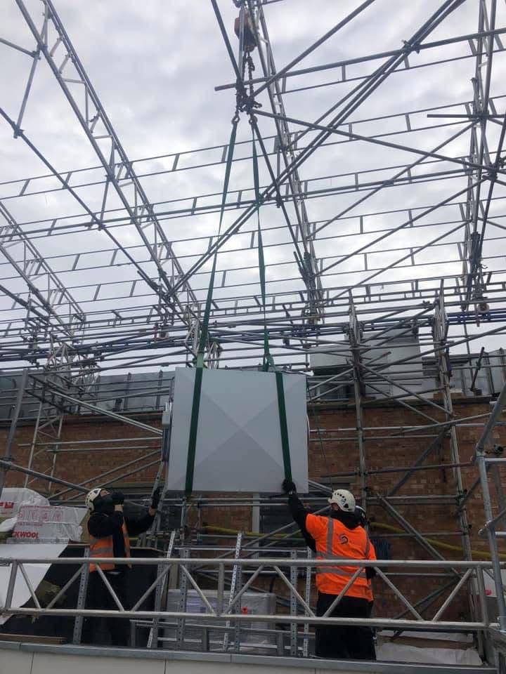 Engineers lifting HVAC unit on scaffolding